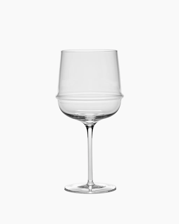 The Dune Red Wine Glass by Serax is a clear, empty artisanal glass featuring a wide bowl, a gentle bulge around the middle, and a long, slender stem, set against a plain white background.