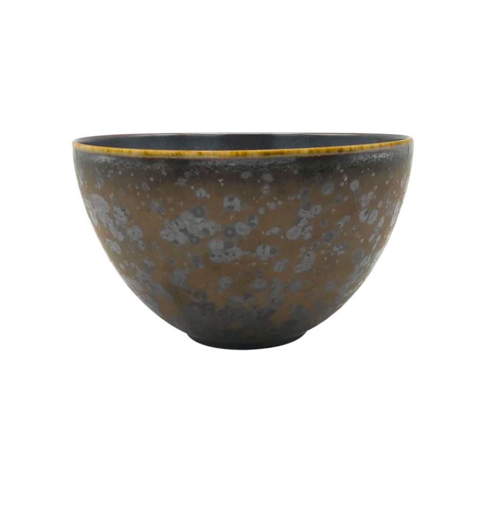 The Aguirre Dinnerware by Jaune De Chrome features a ceramic bowl with a dark brown and gray speckled pattern, rounded sides, and a yellowish rim that evokes the timeless elegance of French dinnerware, set against a plain white background.