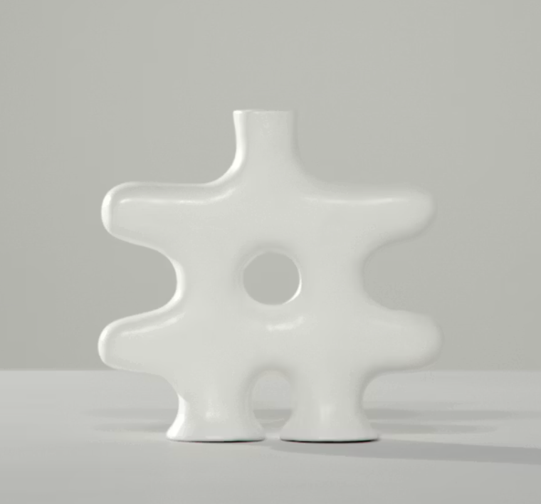 The Nedjma Vase by Schwung Design features a handcrafted ceramic form with a central hole and four rounded protrusions, displayed on a light gray surface against a plain gray background for an artisan-made accent.