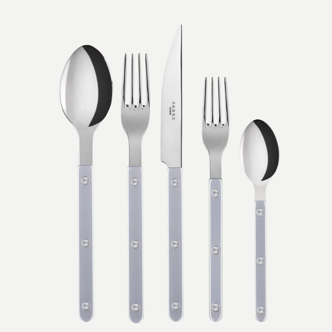 Five pieces from the Sabre Bistrot Pearly 5 Piece Setting - Shiny—including a spoon, fork, knife, salad fork, and teaspoon—each featuring metallic accents and pearlescent handles with round rivets, are arranged in a row on a white background. Expertly crafted in France.