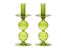 The Bella Candlestick Holder Set of 2 by Kim Seybert showcases two hand-blown green glass candlestick holders, each featuring a ribbed design with two stacked round segments and scalloped detailing on both the base and candle cup, elegantly presented against a white background.