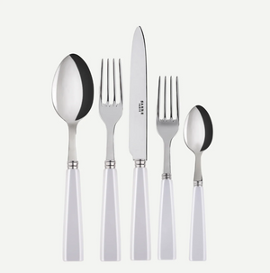The Sabre Icone 5pps w/ Serrated Knife by Sabre features five dishwasher-safe stainless steel pieces with white handles—tablespoon, dinner fork, serrated dinner knife, salad fork, and teaspoon—arranged in a row on white.