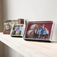 Framed photographs on a white shelf against a plain wall