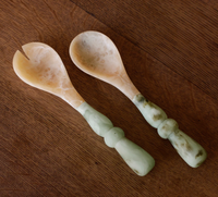 The Beatriz Ball Resin Giada Salad Server Set - Jade Swirl features a fork and spoon with jade swirl handles and marble-style heads, shown side by side on wood—perfect for serving in style.