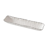 The Portofino Plata Cracker Tray by PAMPA BAY is a long, narrow white ceramic tray with textured, wavy edges and a hammered surface, shown angled on a white background.