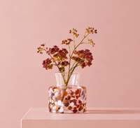Small Meadow Vase Fall by Orrefors Kosta Boda with a multi-colored speckled pattern containing a stem of small dark red flowers.