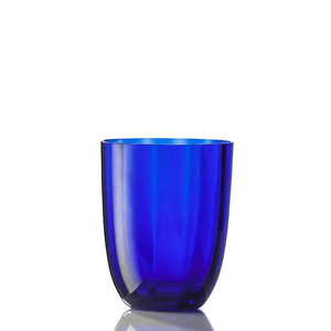 The Idra Tumbler Optic by Nason Moretti, crafted from translucent deep blue glass, stands upright on a reflective white surface against a plain white background.
