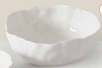 The Willow White Bowl by PAMPA BAY is a white ceramic bowl featuring an irregular, wavy rim and a smooth, glossy finish, displayed against a light background.