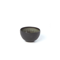 A small, round, black Tourron Samoa bowl by Jars - Rosenthal features a glossy, textured ceramic interior and matte exterior, reminiscent of artisan stoneware, placed on a white background.