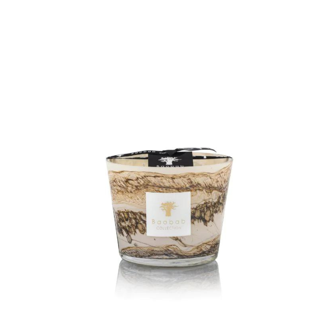 The Baobab Sand Siloli Candle is a hand-blown glass candle with swirling brown, cream, and beige patterns, labeled on the front and topped with a black ribbon. This scented candle is shown against a white background.