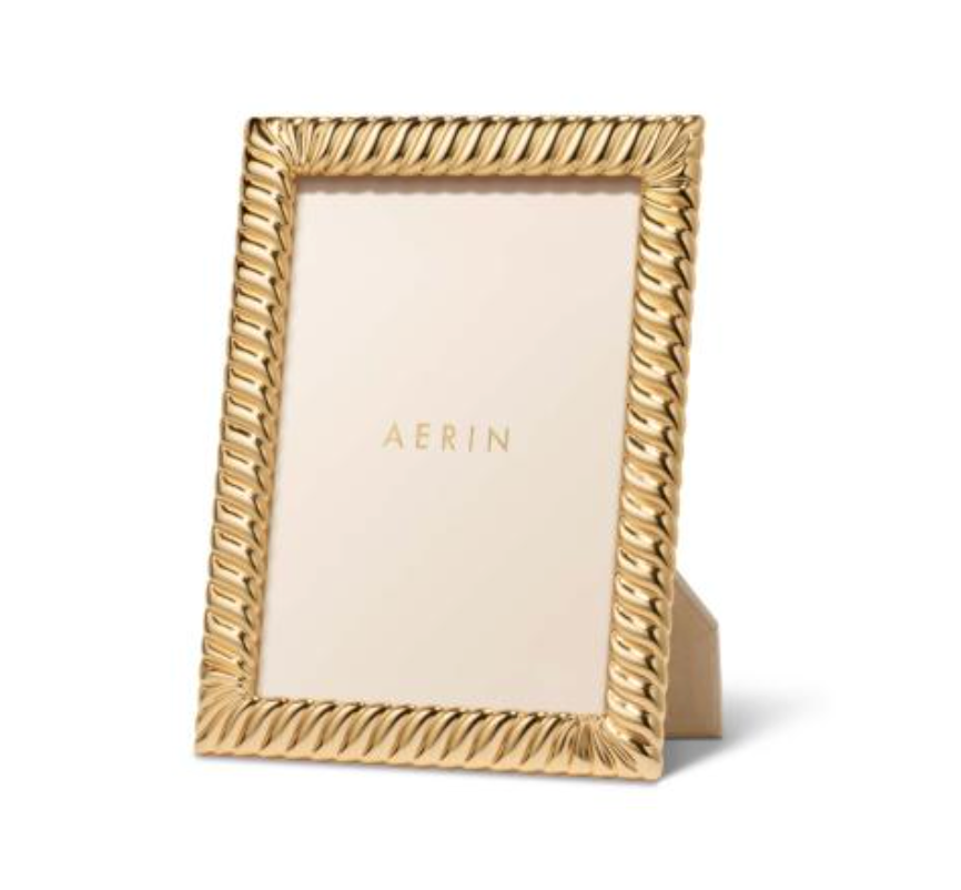 The Aerin Loretta Frame Gold features a twist design around the edges and displays a blank insert with "AERIN" in gold letters, standing upright on a white background. Ideal as a 4x6 photo frame.