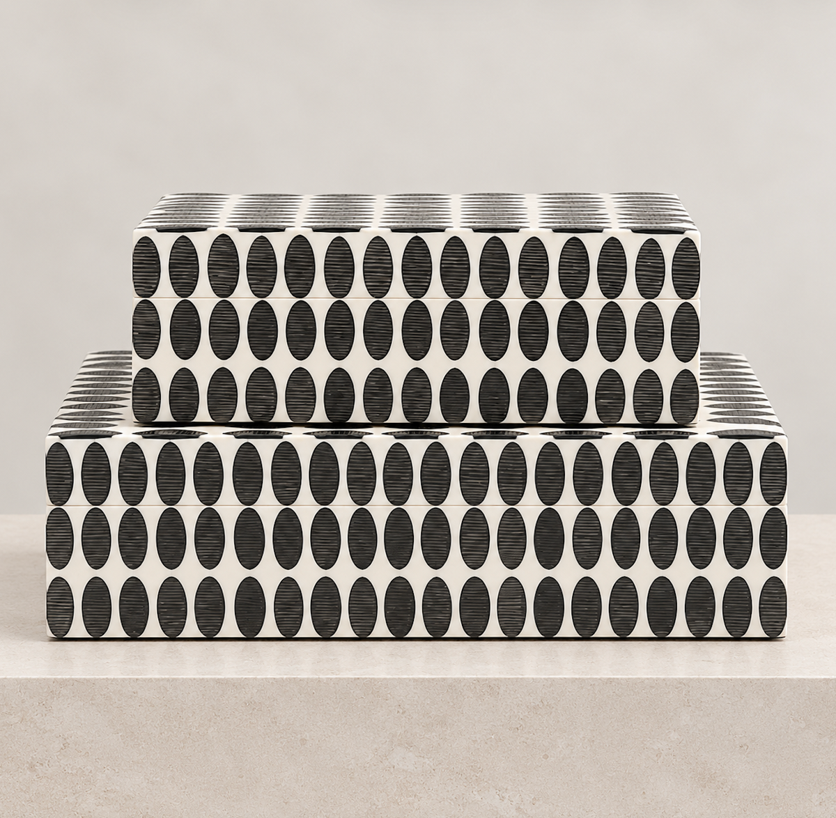 Two rectangular Thumbnail Boxes by A Sanoma Inc, featuring a black oval and white striped geometric pattern, are stacked on a light-colored surface against a plain beige background. These stunning handcrafted storage boxes serve as elegant decorative accents, elevating any room.