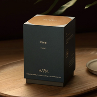 A dark teal Hara (Home ) Candle box with gold lettering on a wooden tray.