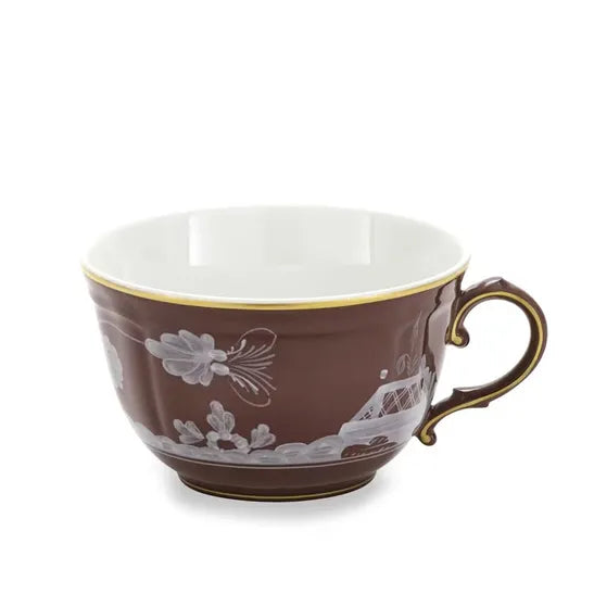 A brown porcelain teacup from the exquisite Ginori 1735 Oriente Italiano Castagna collection, featuring a gold rim and handle and adorned with white floral and landscape patterns. Expertly crafted in Italy, the cup is displayed against a white background.