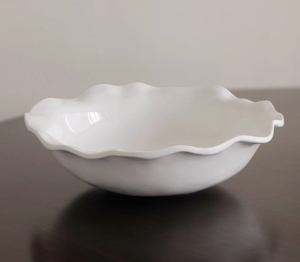 The Beatriz Ball Vida Havana Pasta Bowl White - Large features a wavy, scalloped edge and rests on a dark wooden surface with a plain, light background.