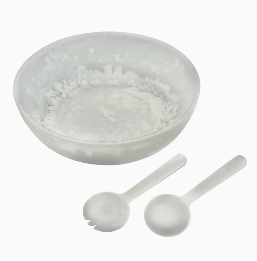 The Eddy Resin Bowl With Servers by Inspired Generations, featuring a stylish bowl paired with matching serving spoon and fork, creates an elegant salad set on a white background—making it a perfect housewarming gift.