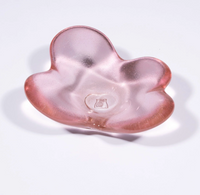 The Cloud Dish by Tyler Barry Design is a hand-blown, pink translucent glass bowl with three rounded lobes and an organic shape. Displayed on a white background, it features a small emblem at the center for added detail.