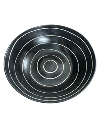 The Linea Bowl Black by Michael Wainwright is a black ceramic bowl featuring white concentric circles decorating its interior, as seen from above.