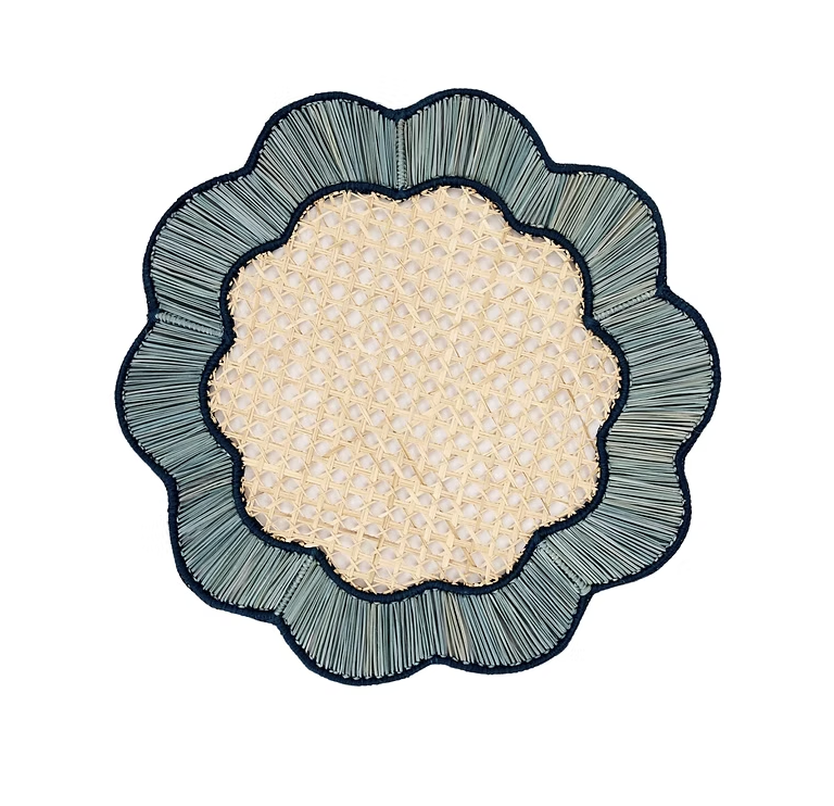 The Coro Cora Breezy Placemat Set of 4 in Sky Blue & Navy features round, flower-shaped mats with a woven beige center and scalloped embroidered edges—ideal handcrafted pieces for an elegant organic table setting.