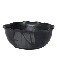 The Leona Bowl - Marina by CDMX / MASA TALLER is a black ceramic serving bowl featuring a wavy, scalloped rim and a subtly textured surface. Set against a plain white background, this piece makes an elegant and striking decorative accent for any setting.