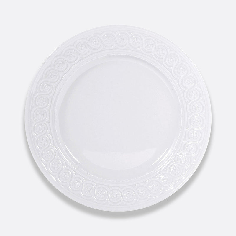 The Louvre Dinnerware by Bernardaud is a round, white ceramic plate featuring an ornate, Renaissance-inspired embossed border, showcased against a plain light gray background.