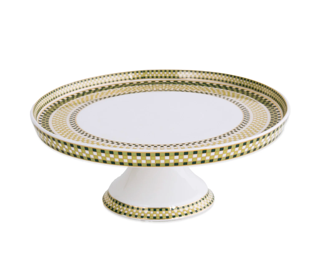 The Beatriz Ball Ceramic Ravenna Pedestal Cake Plate - Green & Gold features a wide, flat white surface on a short pedestal base, beautifully adorned with green and gold checkered and geometric patterns around the edge.