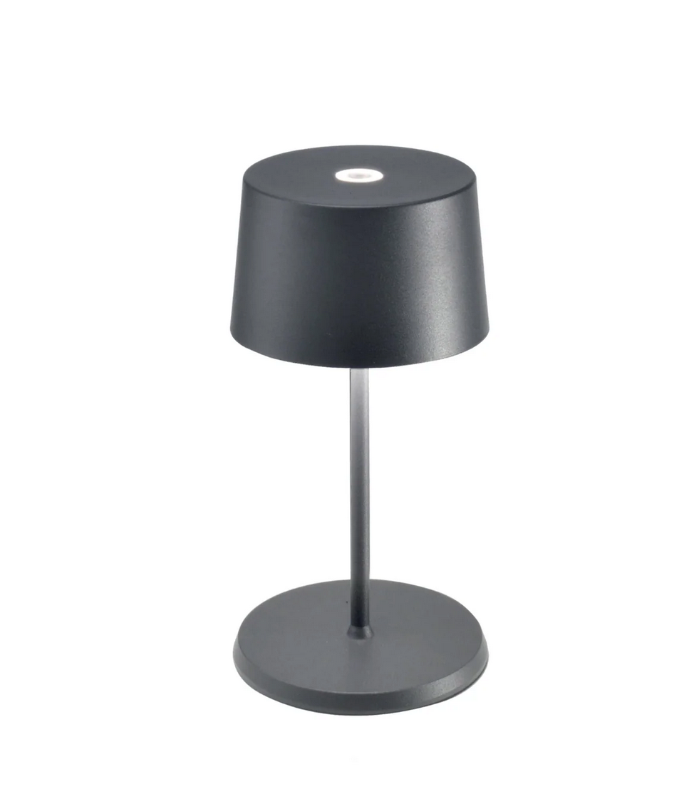 The Zafferano Olivia Mini Table Lamp features a modern, minimalist design in dark grey, with a conical shade, slim stem, and round base. It’s rechargeable and cordless.