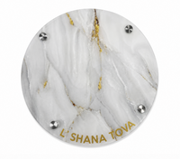 The Eye Candy Round Challah Board in White/Gold/White features a luxurious round marble design with gold veins, four metal screws, and “LSHANA TOVA” elegantly inscribed in gold at the bottom. This sophisticated piece is a perfect addition to your holiday table, making it ideal for serving round challah during festive celebrations.