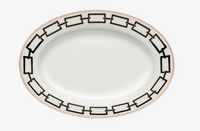 The Catene Nero Dinnerware by Ginori 1735 features an oval white plate adorned with a black geometric chain pattern around the rim and accented by a thin gold border on the edge.