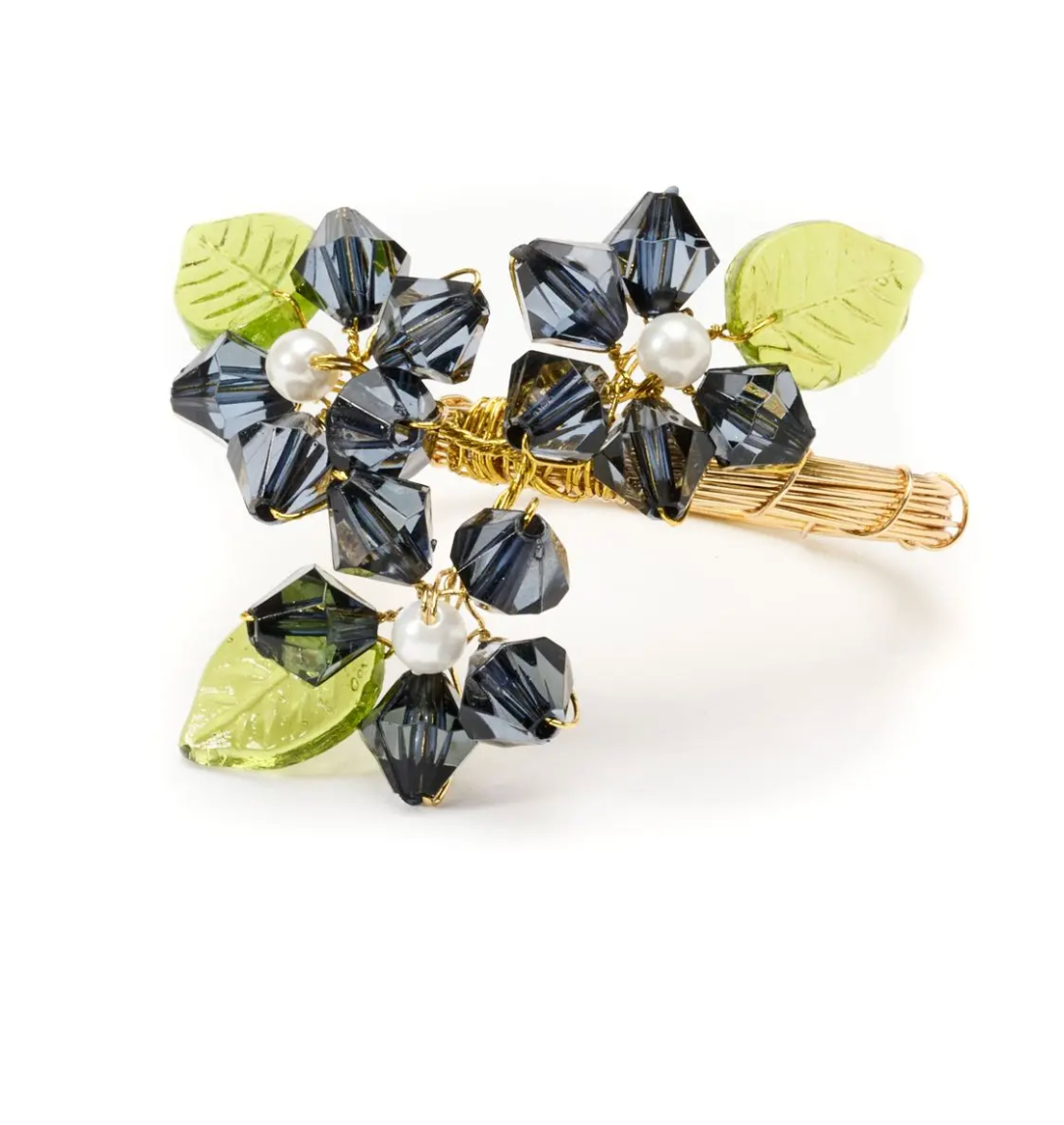 The Deborah Rhodes Floral Spray Napkin Ring Set of 4 features flower designs with dark crystal beads, white pearl centers, and green glass leaves on a gold-toned base—ideal for fans of elegant details and beaded décor.