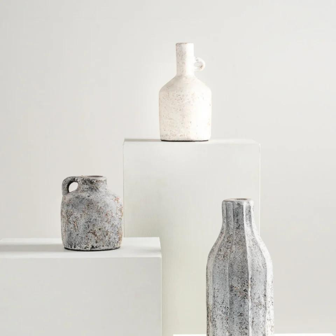 Kennedy Vase - White is shown here on a pedestal along with two dark colored vases. 