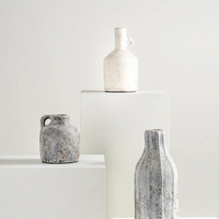 Kennedy Vase - White is shown here on a pedestal along with two dark colored vases. 