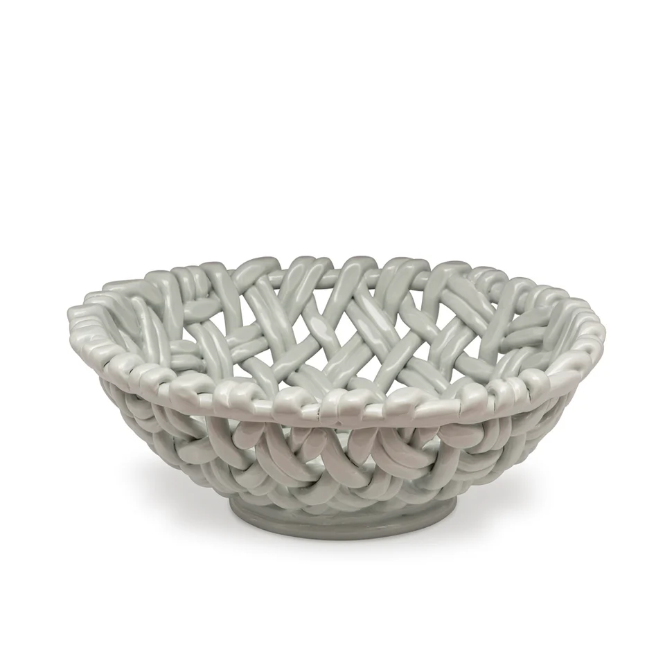The Skyros Woven Basket - Round-15" is a glossy, light gray ceramic bowl featuring an open, basket-inspired motif with thick, interlaced ribbons.