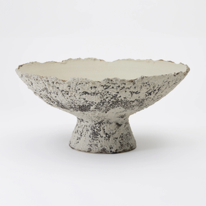 The Joelle Bowl by Dumae features a textured, footed design with a wide, flared rim. Its mottled gray and white exterior has a Sierra finish, while the smooth off-white interior highlights expert hand-crafted ceramic artistry.