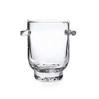 The Simon Pearce Manchester Ice Bucket is crafted from clear glass with two small, rounded handles on opposite sides, shown against a white background.