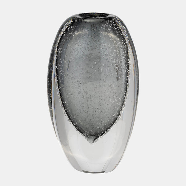The Orbit Vase Smoke by Sagebrook Home features a rounded, elongated clear glass design with small air bubbles embedded in the thick glass for a textured, artistic effect. Displayed against a plain light gray background.