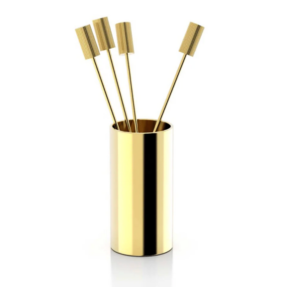 The Striations Cocktail Picks s/4 in Holder by Anna New York features four gold stainless steel picks with textured rectangular tops, displayed in a shiny gold cylindrical holder against a white background.