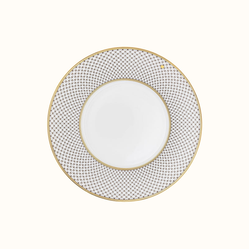 The Mottahedeh/Robert Haviland Home Dinnerware- Gold plate features a round white design with a wide blue and white geometric rim, thin gold trim on the edge, and a plain center.