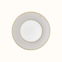 The Mottahedeh/Robert Haviland Home Dinnerware- Gold plate features a round white design with a wide blue and white geometric rim, thin gold trim on the edge, and a plain center.