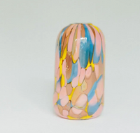 Add a unique touch to your home decor with the Jelly Baby Mini Vase Collection by Maria Ida Designs—a tall, cylindrical ceramic vase featuring a glossy finish and abstract brush-like patterns in pink, yellow, blue, and tan on a white background. This statement piece beautifully complements your glass blown mini vases or other handmade art glass objects.