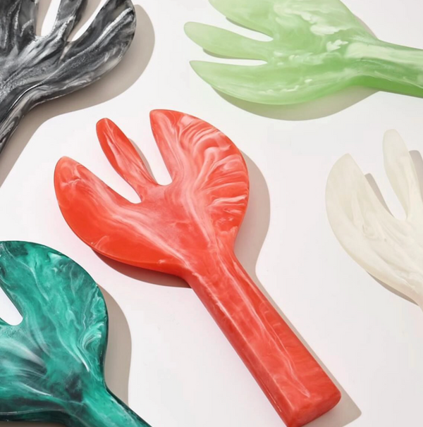 Swirl Colored Resin Jumbo Servers by Nashi Home in green, red, white, black, and teal, featuring wide handles and three-tined fork ends, are displayed on a flat surface.