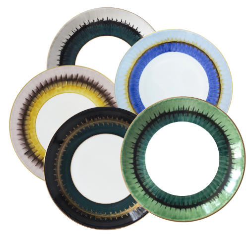 The Marie Daage Aloe Dinnerware by Marie Daâge includes five ceramic plates with intricate, colorful rims in green, blue, yellow, black, and brown tones, arranged in an overlapping fan-like pattern on a white background.