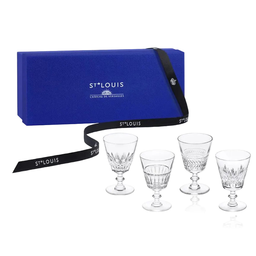Four clear cut-glass goblets displayed in front of a blue St. Louis gift box with a black branded ribbon on a white background.