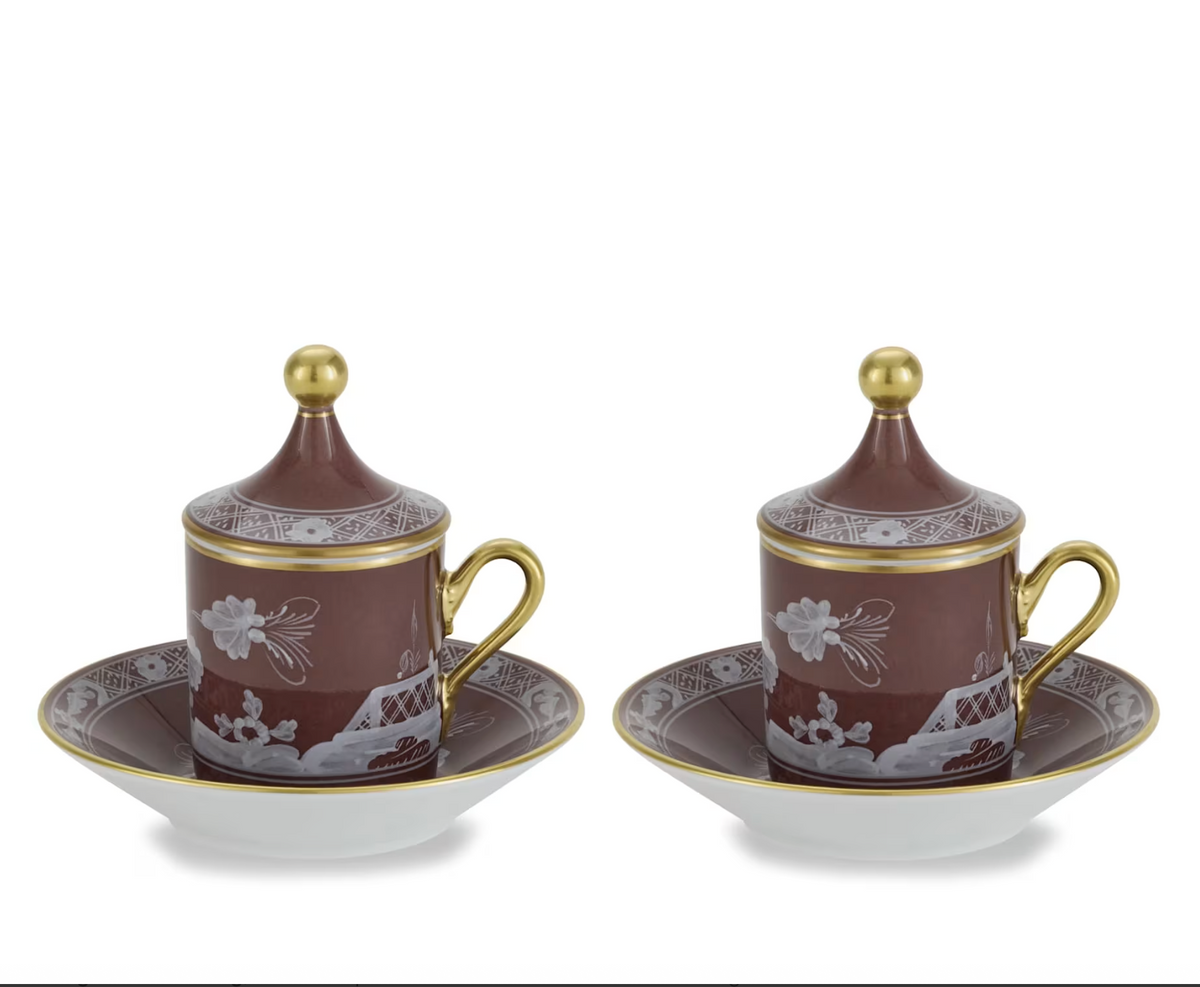 Two Ginori 1735 Oriente Italiano Castagna lidded espresso cups and matching saucers in brown with white floral patterns and gold rims and finials.