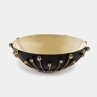 The Luho Eden Bowl features a matte black exterior, a glossy gold interior, and gold rod and sphere accents for an elegant, modern look. This food-safe accessory combines sophistication with contemporary style.