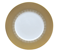 The Sol Dinnerware plate by Bernardaud features glossy white Limoges porcelain with a wide 24k gold rim adorned in a radiating line pattern, giving this elegant piece its signature decorative appeal.