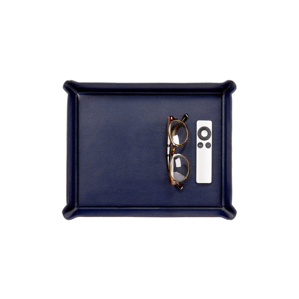 A rectangular navy blue Leather Ottoman Tray containing a pair of eyeglasses and a white remote control.