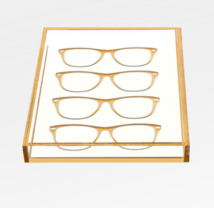 The Eye Candy Specs Eyeglass Tray is a clear luxury tray with a gold border, elegantly displaying four pairs of eyeglass frames in two neat rows on a white background.