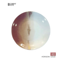 The Marie Daâge Horizon Gold Dinnerware plate is round, porcelain, with a gradient in brown, gold, and white tones. A gold stripe runs vertically down the center. "CURRENT HOME," "48," and "HORIZON GOLD" are on the corners. Brand: Marie Daâge.