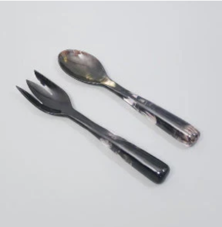 The Vera Horn Server Set by Nashi Home features a spoon and spork side by side on a light surface, showcasing their shiny handles and the elegant handcrafted resin design.